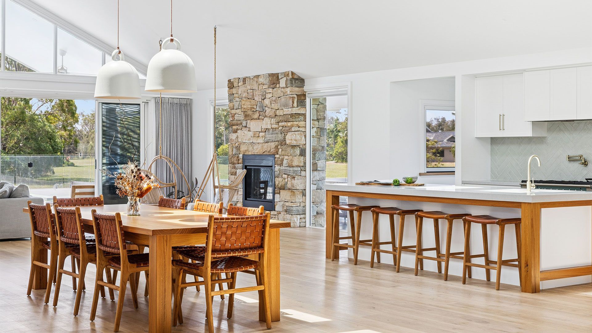 Bright, empty modern room with wood floors, white walls, ceiling fan, and tall windows.