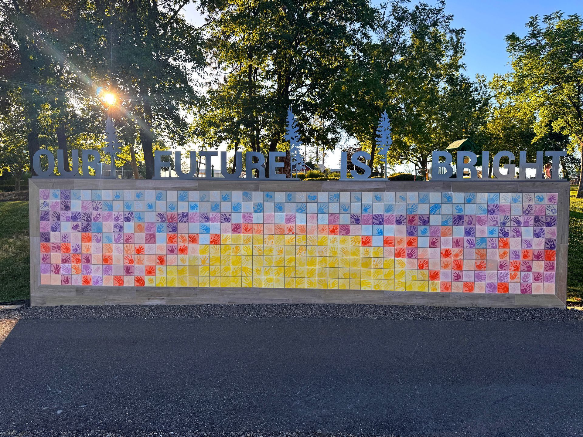 Outdoor mural on a wall reads “THE FUTURE IS BRIGHT” above a colorful mosaic