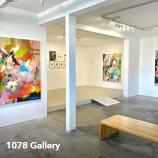 Bright contemporary art gallery with colorful abstract paintings and a wooden bench