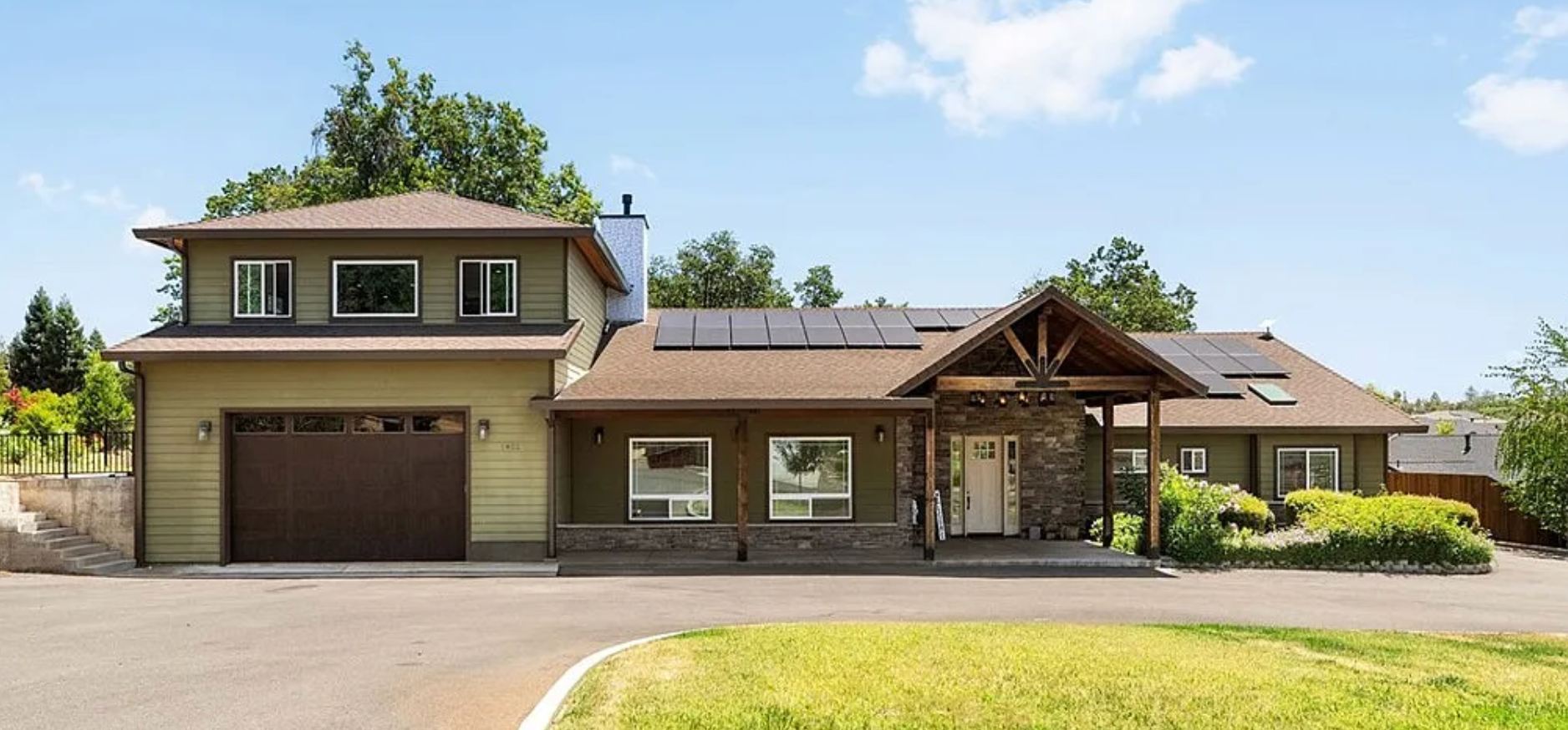 Large beige house with brown garage doors and a covered front entrance on a sunny day