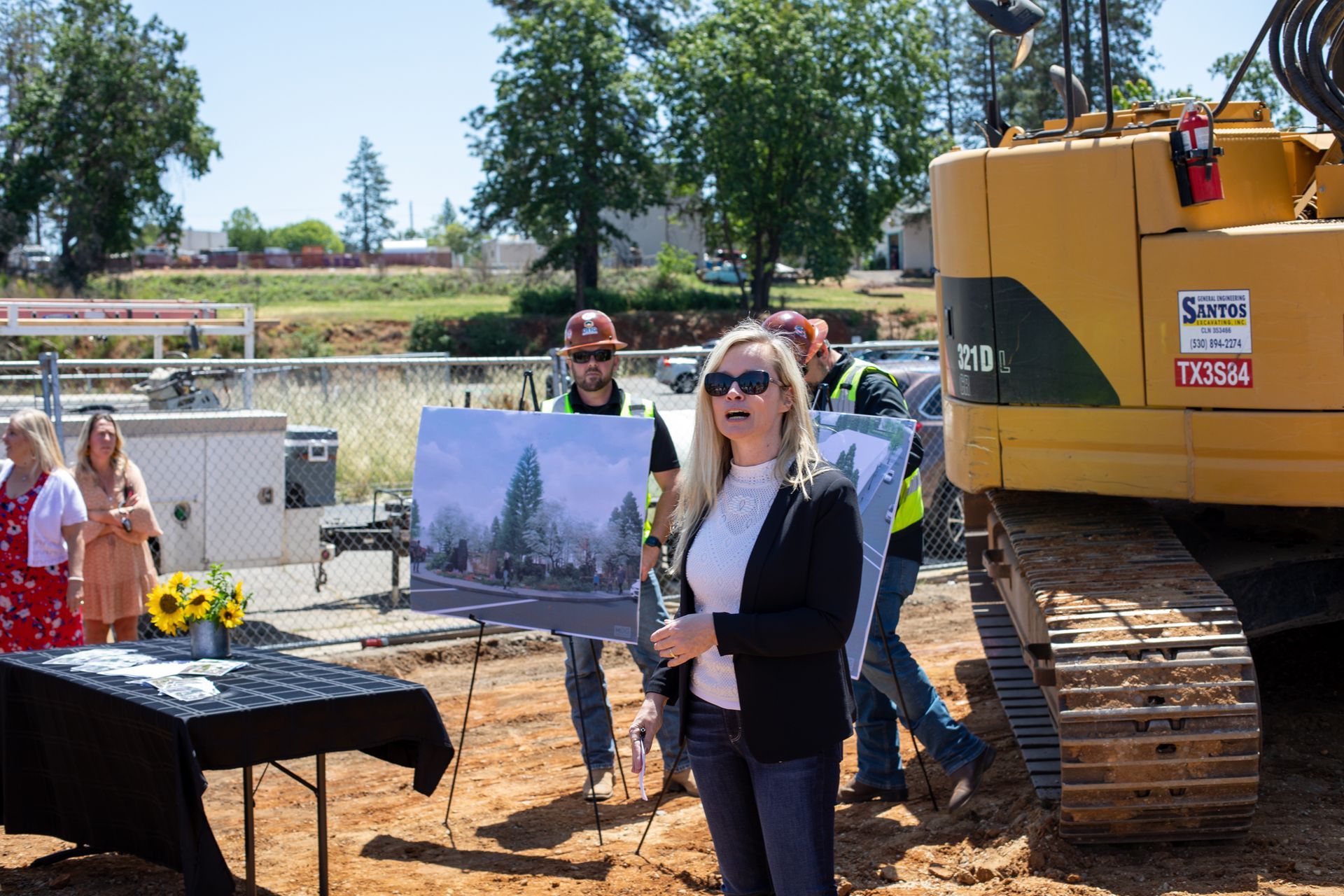 A woman is standing in front of a construction site holding a sign  in Paradise and Magalia, California.