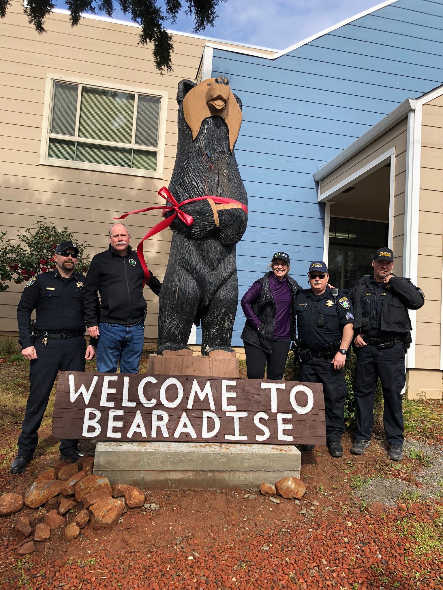 A group of police officers are standing in front of a welcome to paradise sign.