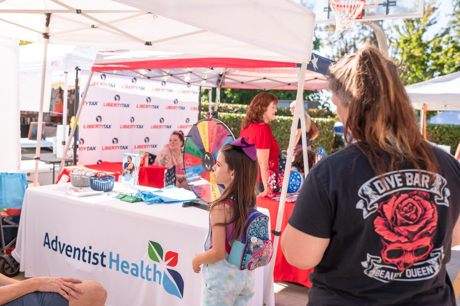 Adventist Health booth at outdoor event with children and a colorful prize wheel