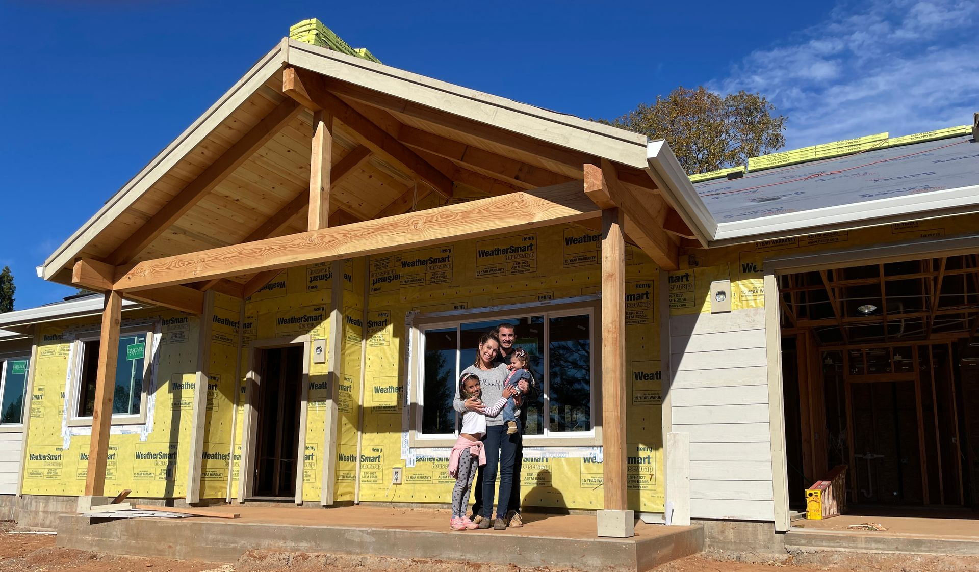 Two people standing at the entrance of a timber-framed house under construction