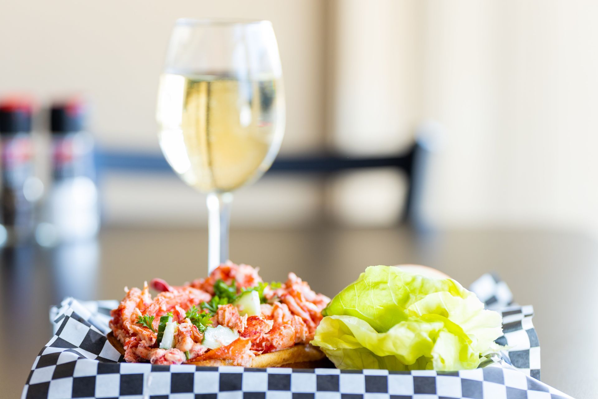 A sandwich and a glass of wine are on a table.