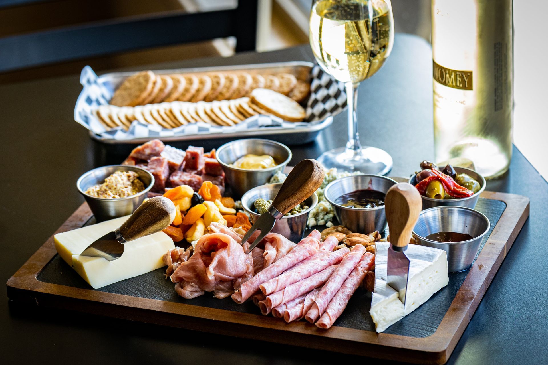 Nic's Restaurant in Paradise California shows a cutting board filled with meat , cheese , crackers and a glass of wine.