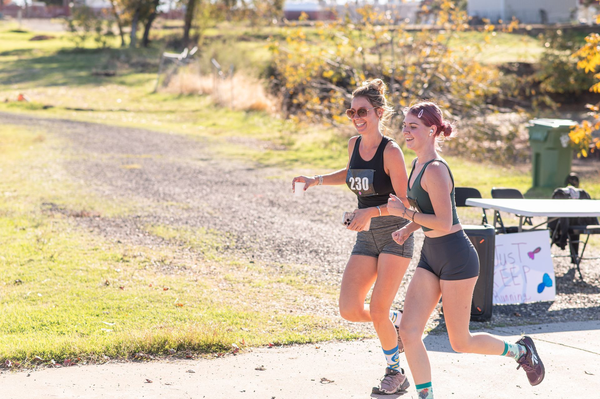 Two runners in black athletic wear racing outdoors on a sunny road
