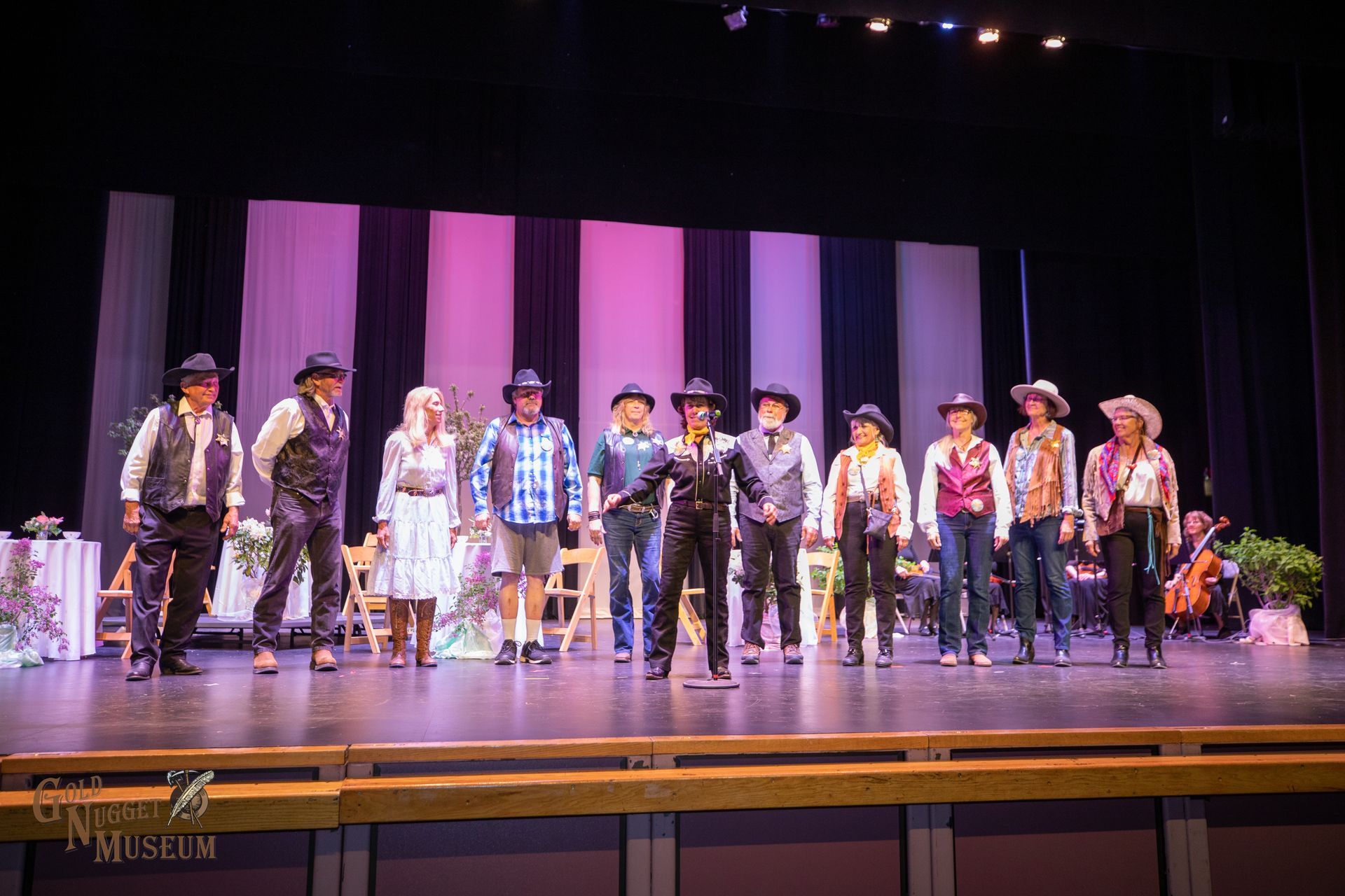 A group of people in cowboy hats are standing on a stage. 
for 