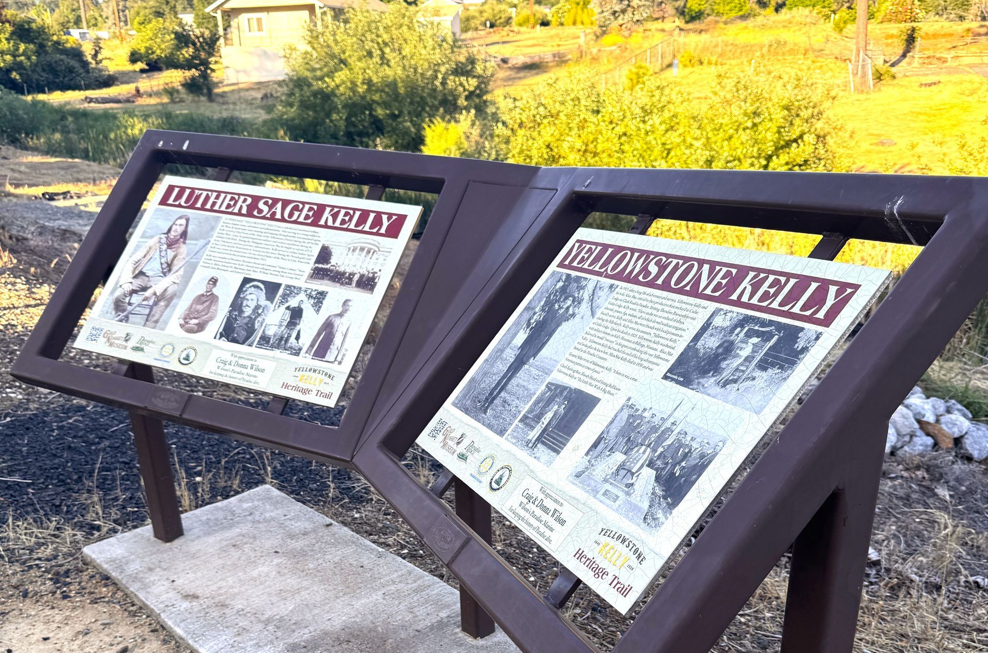Two brown wooden display boards with historical information in an outdoor setting.