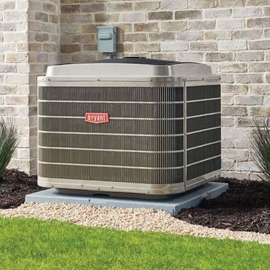 Outdoor air conditioner unit beside a brick house wall and green lawn