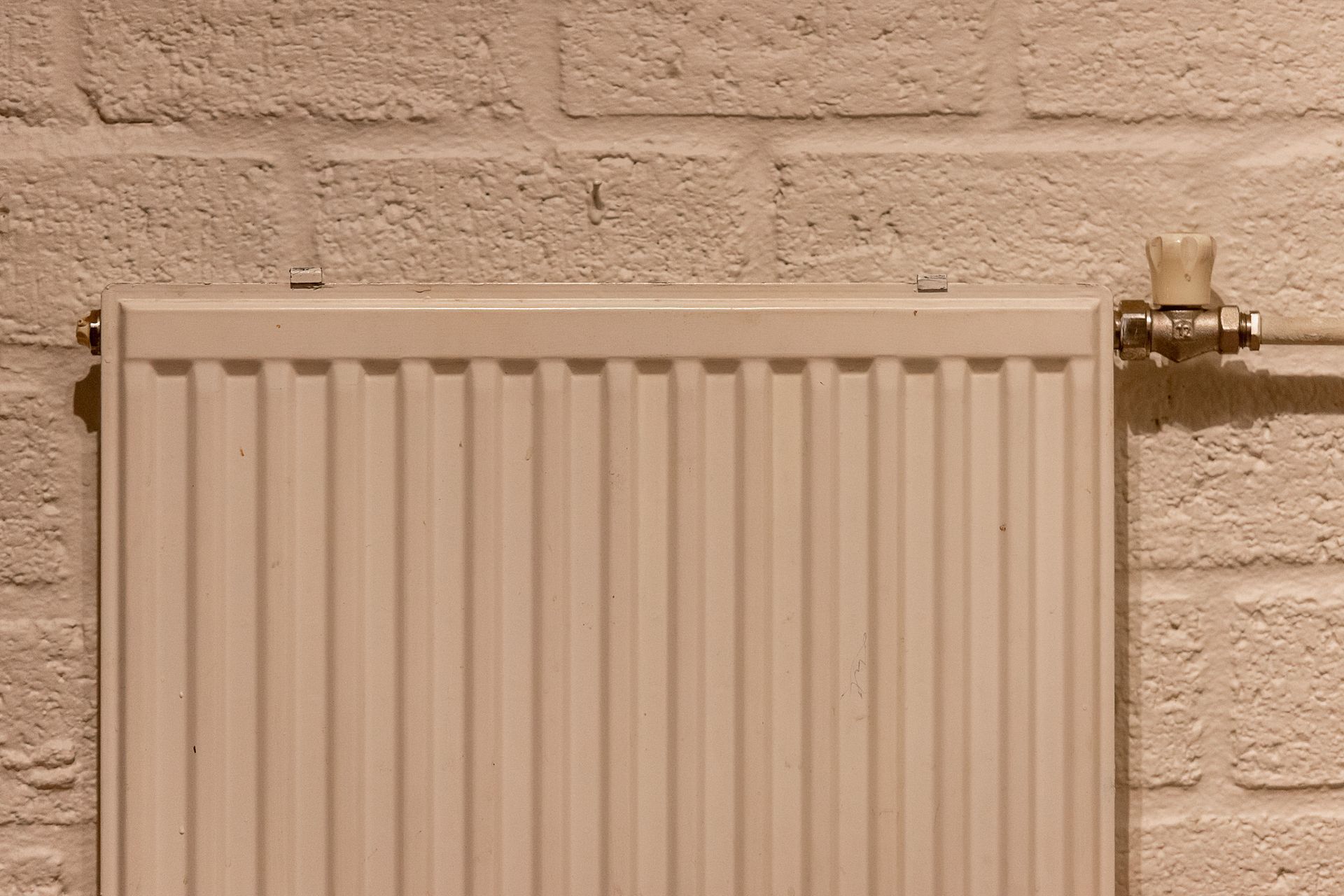 Technician repairing a wall-mounted air conditioner with a screwdriver in a bright living room