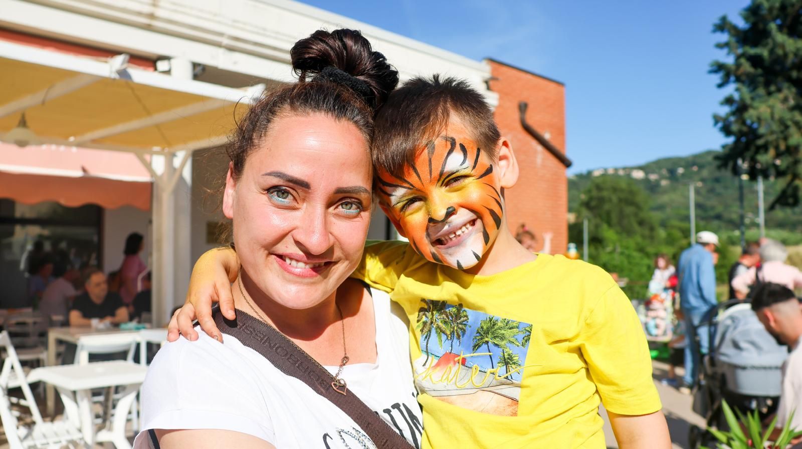 Una donna è in piedi accanto a un ragazzo con una faccia di tigre dipinta sul viso.