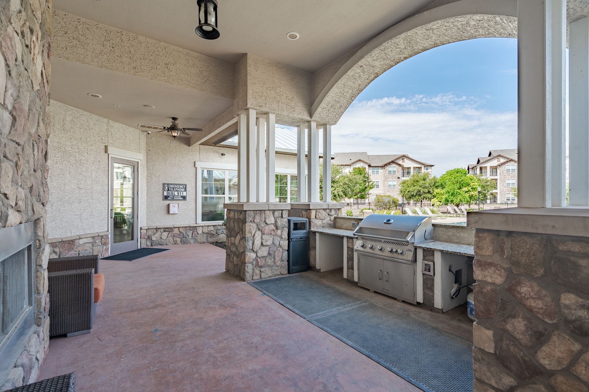 Outdoor communal grilling area under a covered patio with stone columns and a built-in grill at Tradewinds Apartments, offering apartments for rent in Midland, TX near I-20.