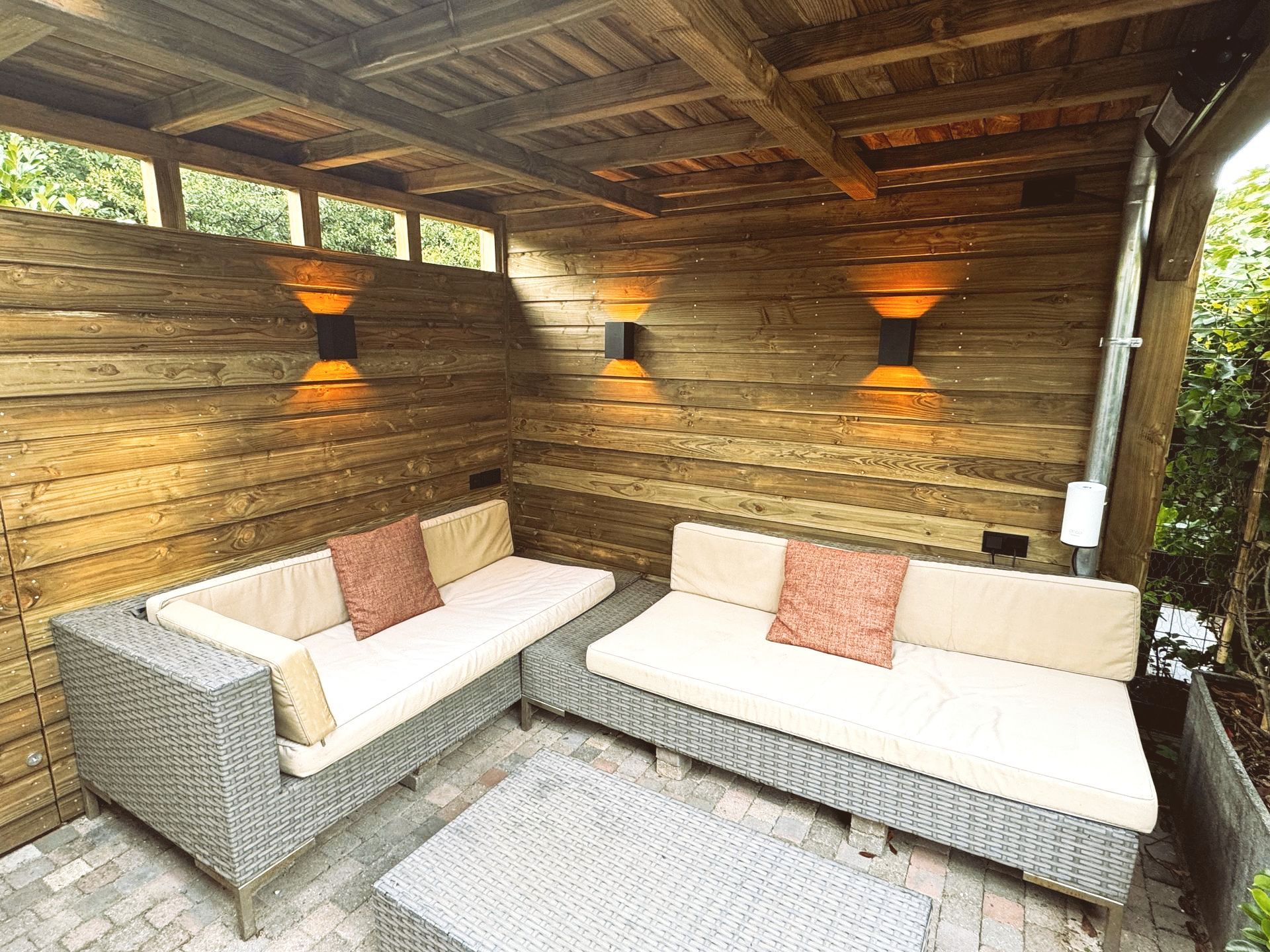 Buiten zitgedeelte met houten lambrisering, banken en wandverlichting.