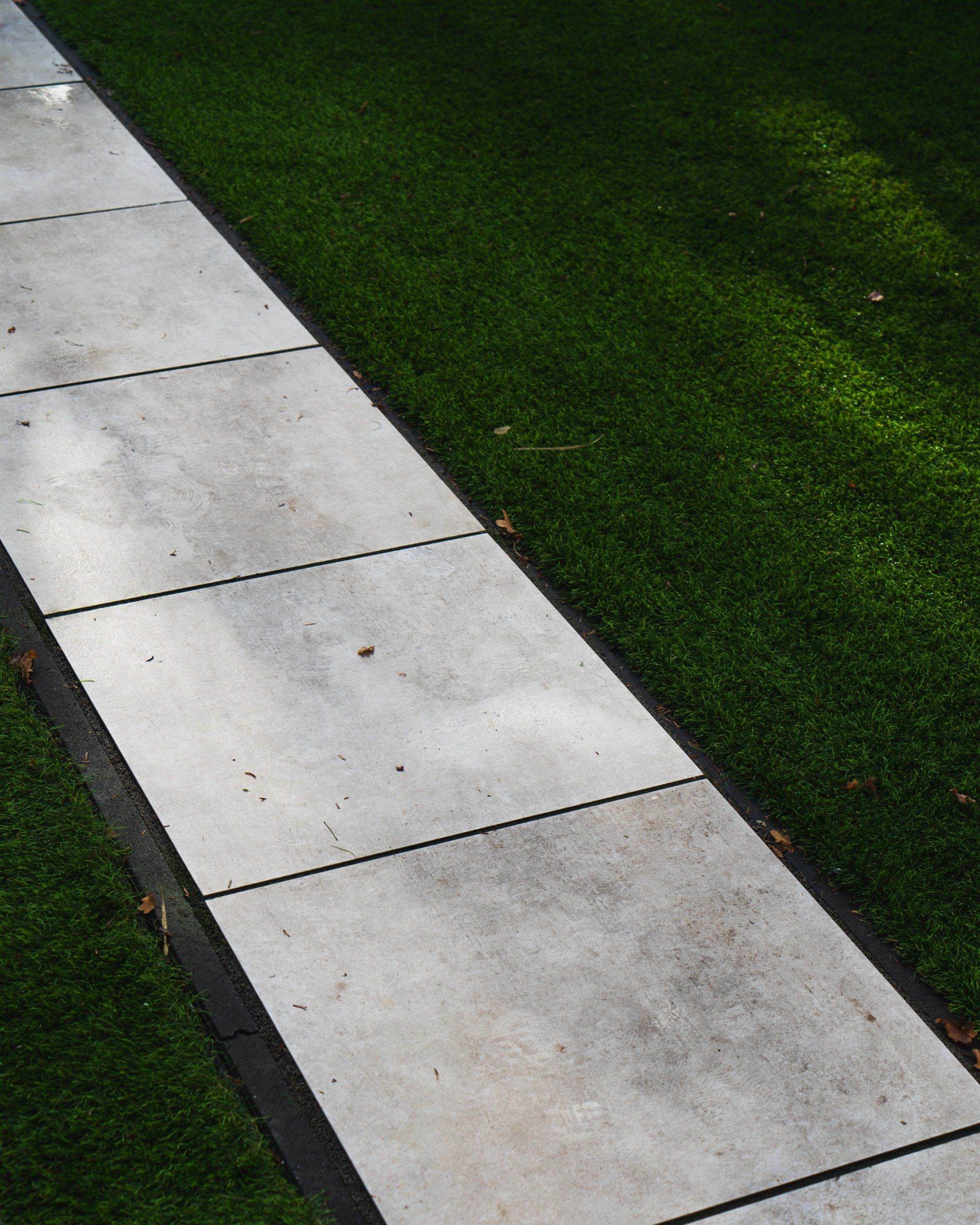 Betonnen trottoir, omzoomd door een groen gazon.