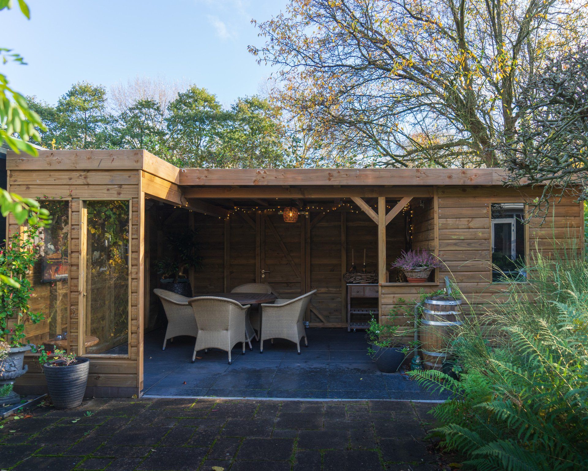 Houten buitenconstructie met zitgelegenheid, verlichting en beplanting.