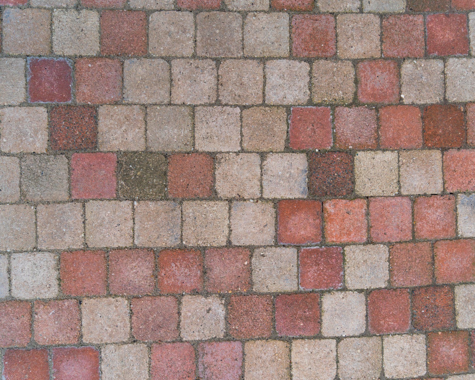 Een terras van bakstenen bestaat uit rode en beige vierkante tegels.