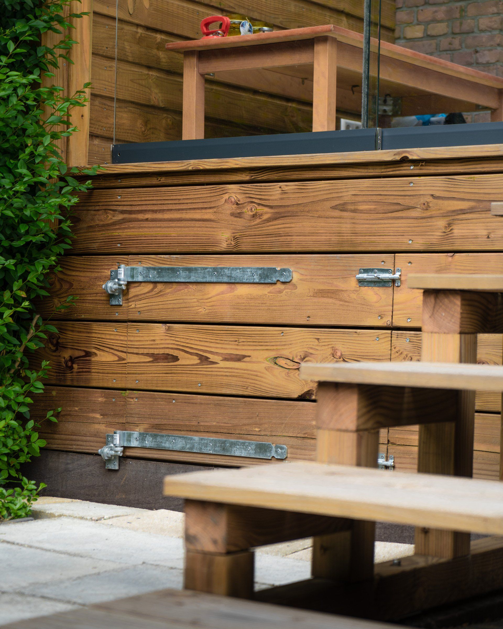 Houten constructie met treden en scharnieren, buitenmeubel met een tafel erop.