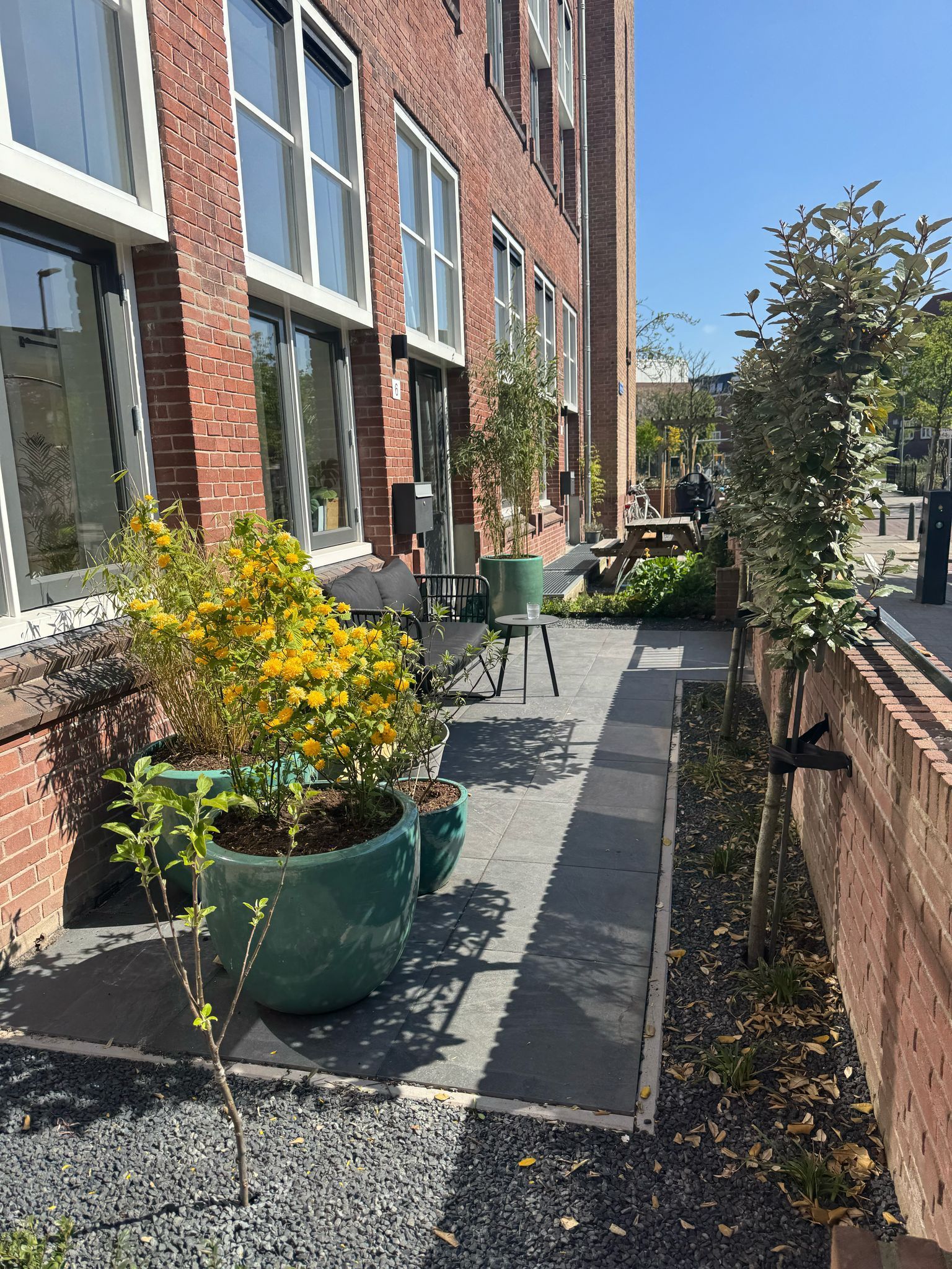 Bakstenen gevel met terras en potplanten.