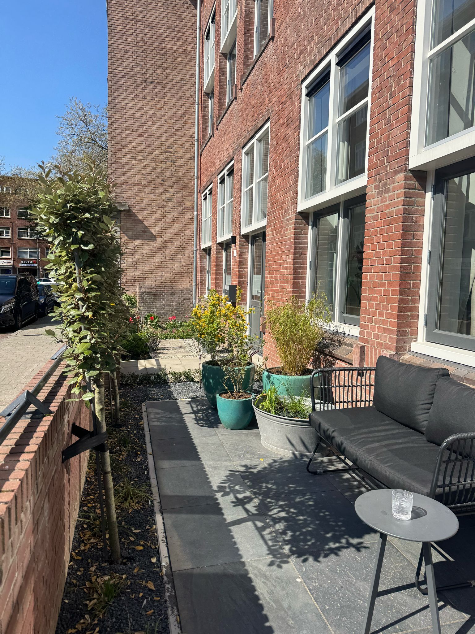 Bakstenen gebouw met ramen, een terras, potplanten en een stoep.