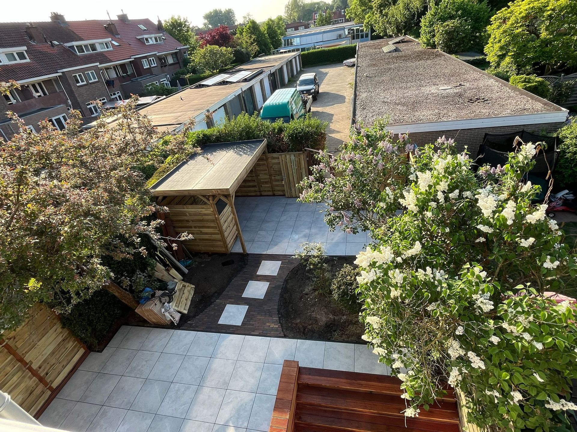 Bovenaanzicht van garages en tuinen met groen, een zonnige dag.