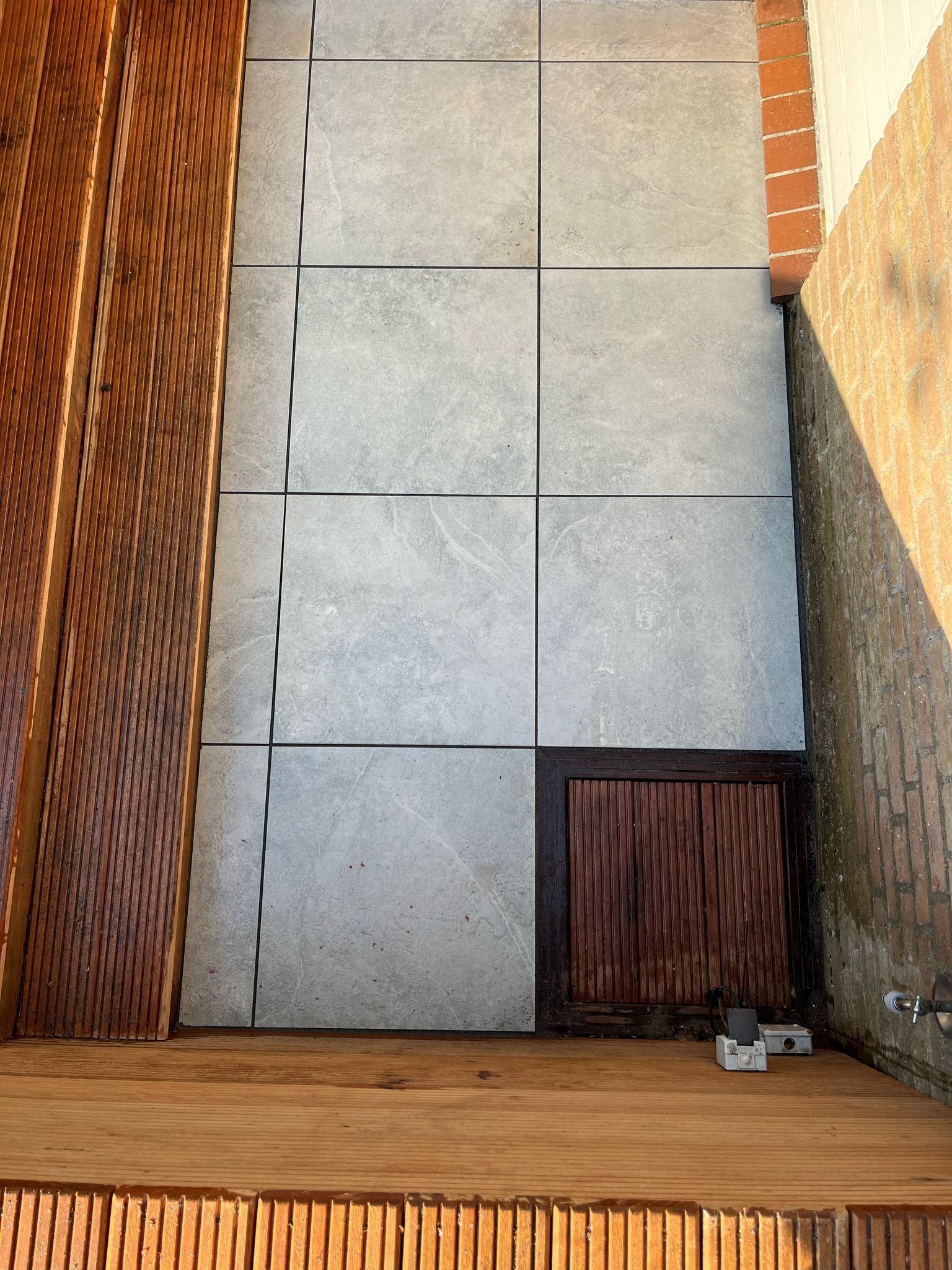 Betonnen terras met bakstenen muur en houten elementen.