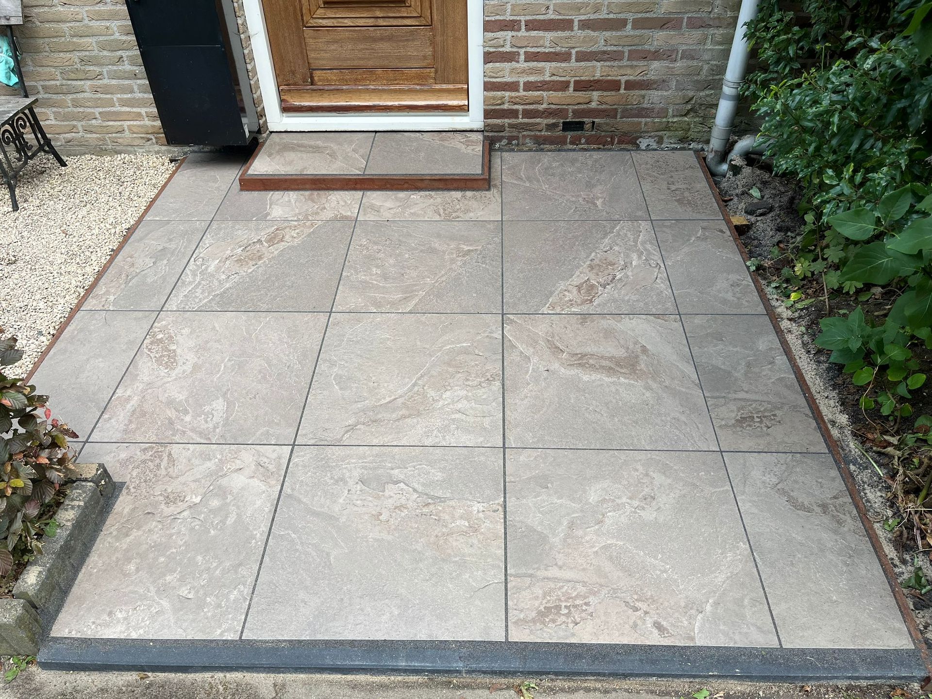 Stenen terras voor een deur met een opstapje.