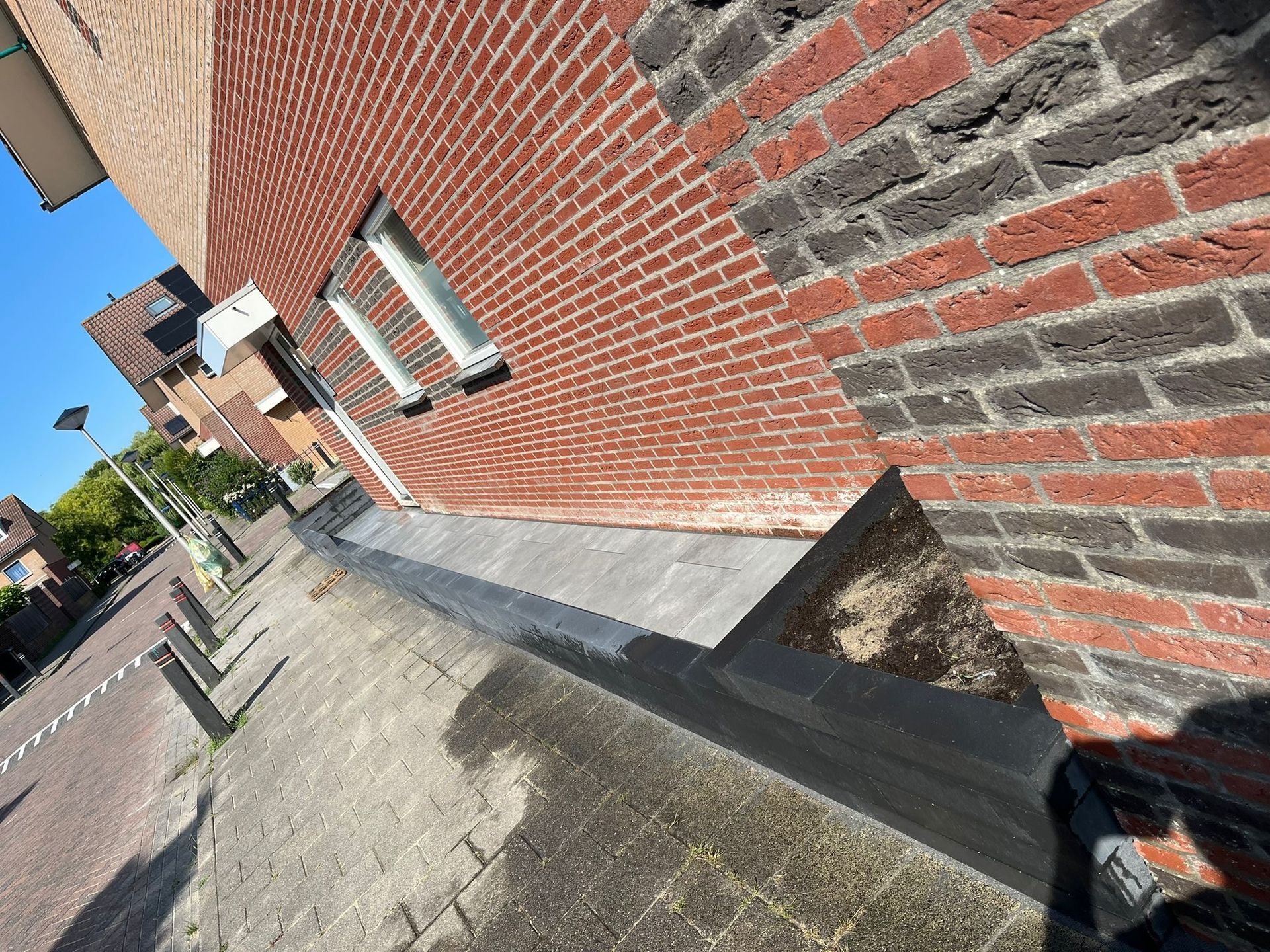 Buitenzijde van een bakstenen gebouw met afgeronde hoeken en een dakgoot.