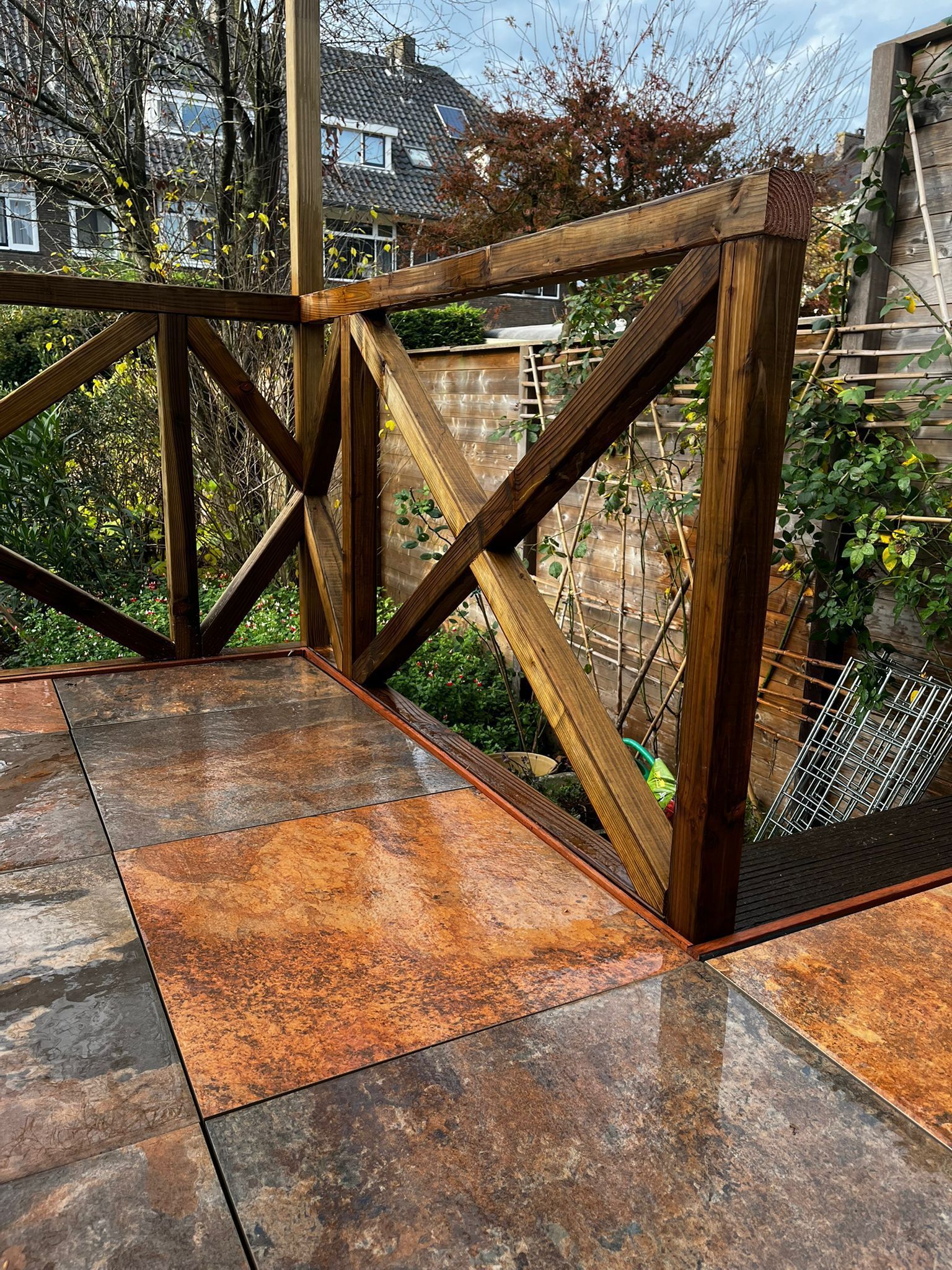 Houten terras met bruine tegels in een patroon en een verweerde houten balustrade.