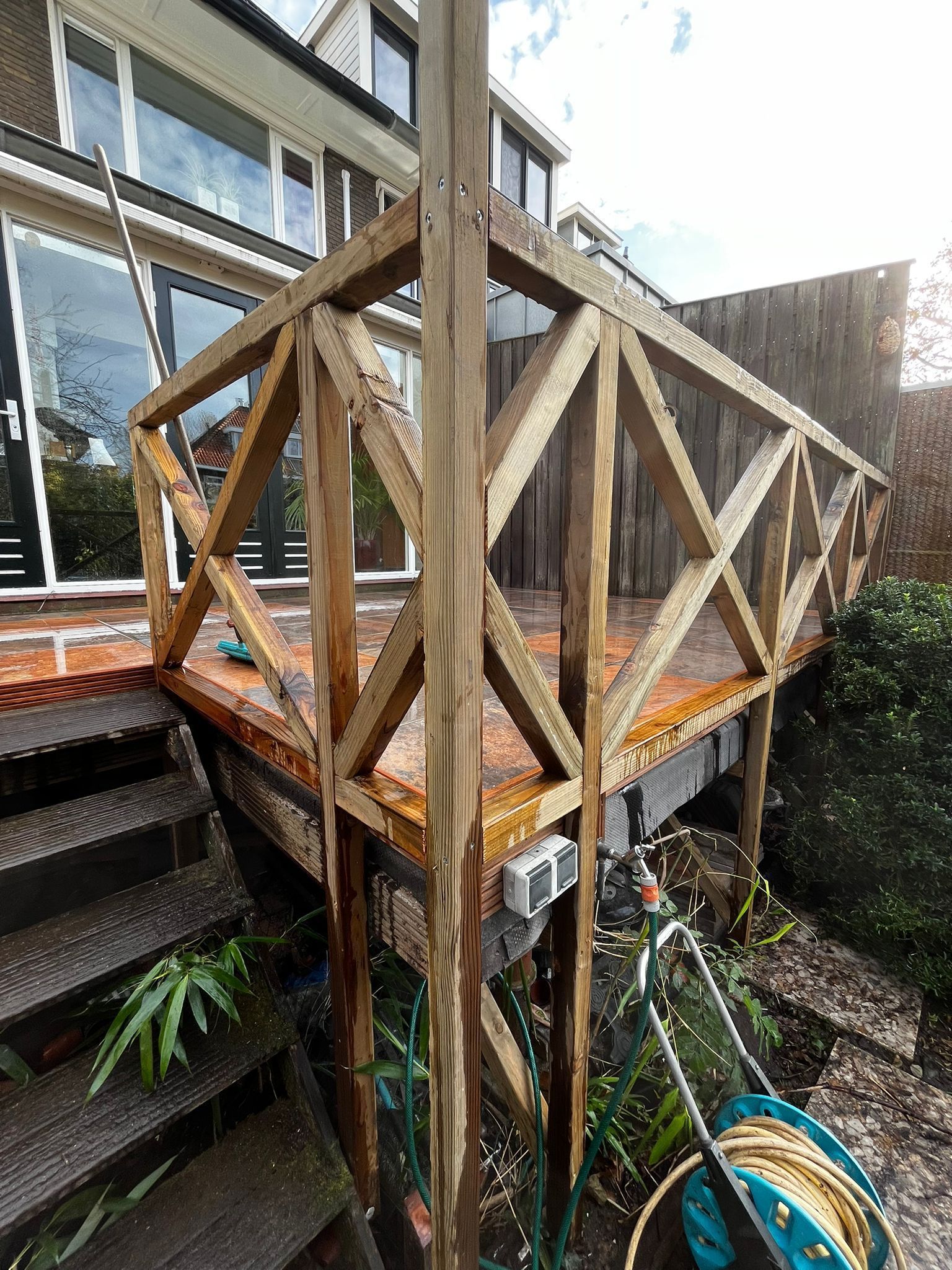 Houten terras met decoratieve balustrade, met uitzicht op een tuin.