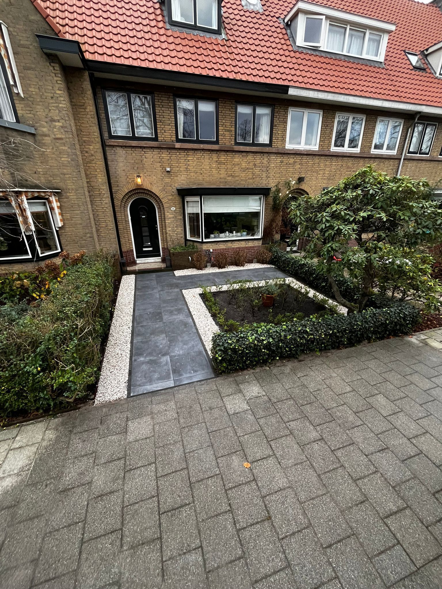 Bruin bakstenen huis met een voortuin en een stenen pad.