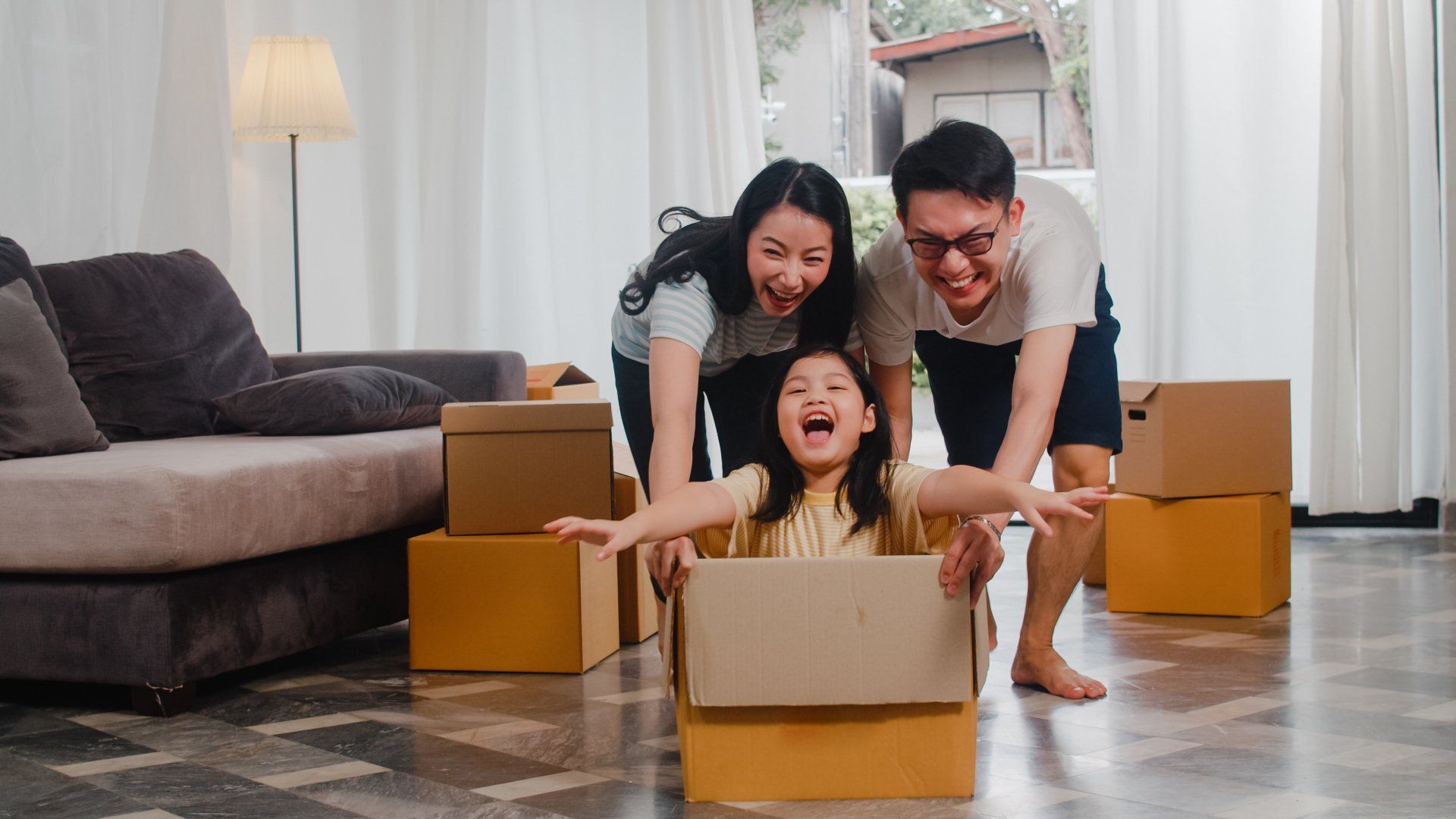 Parents pushing daughter around in box