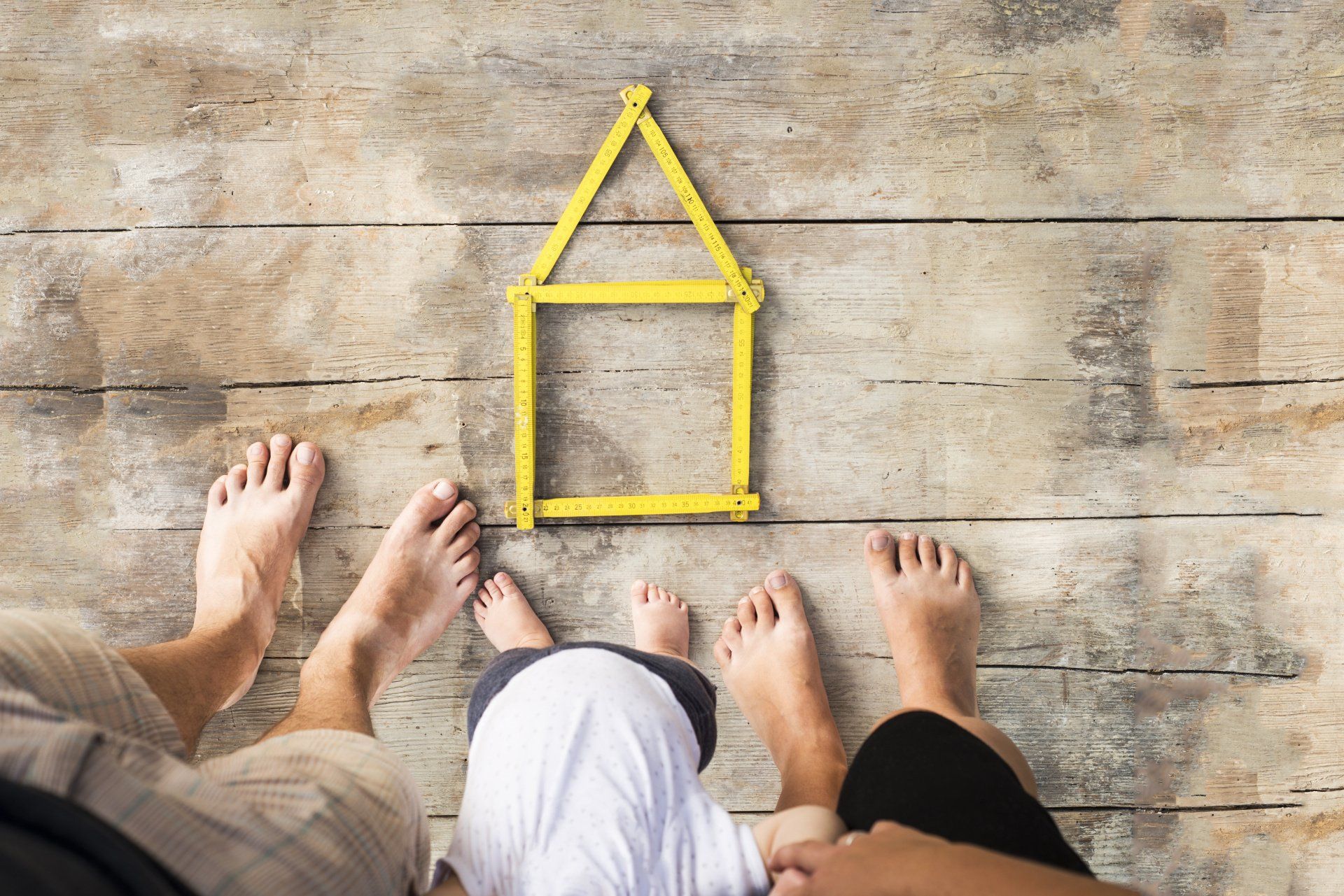Family feet standing around house outline