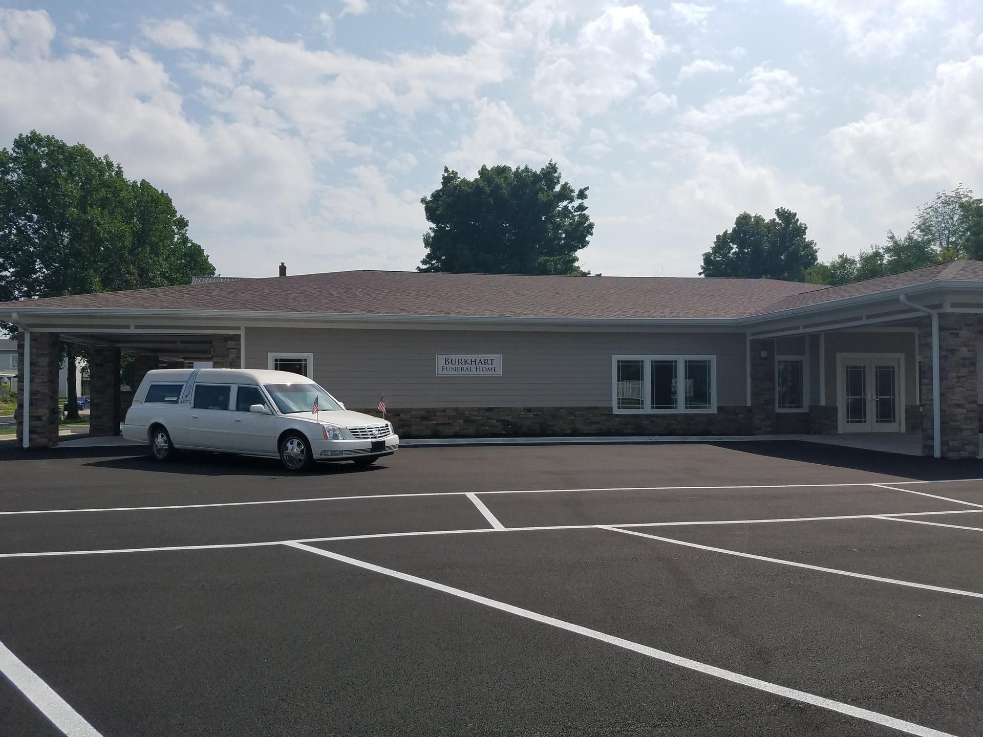 White van parked in front of a low building in an empty lot under a cloudy sky