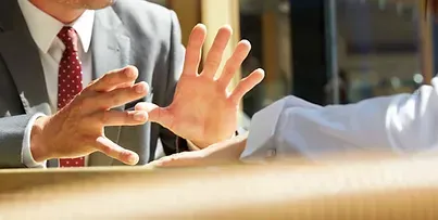 A Man In A Suit And Tie Is Sitting At A Table Talking To Another Man — David Tamanika Solicitors in Ararat, VIC