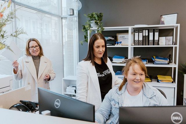 Three Women Are Standing Around A Computer In An Office — David Tamanika Solicitors in Ballarat Central, VIC