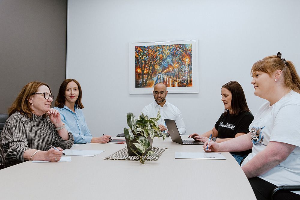 A Group Of People Are Sitting Around A Table In A Conference Room — David Tamanika Solicitors in Ballarat Central, VIC