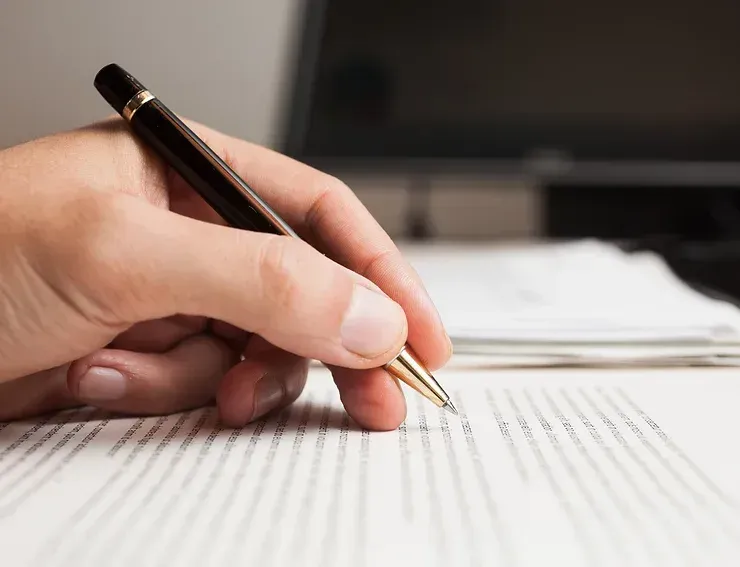 A Person Is Writing On A Piece Of Paper With A Pen — David Tamanika Solicitors in Ballarat, VIC