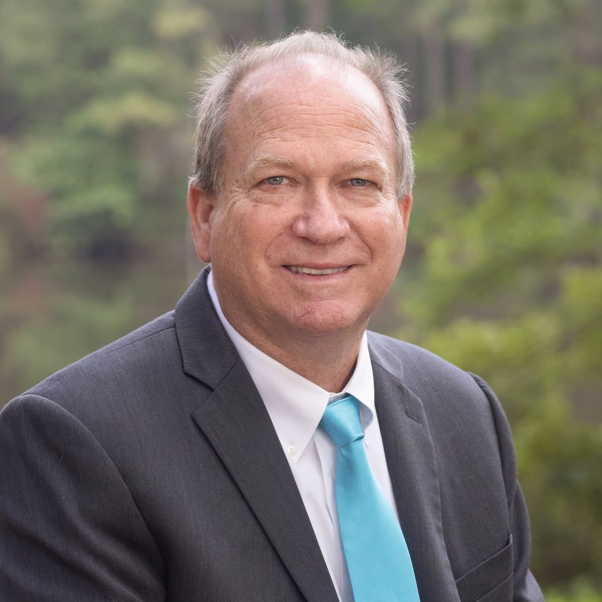 A man in a suit and tie is smiling for the camera