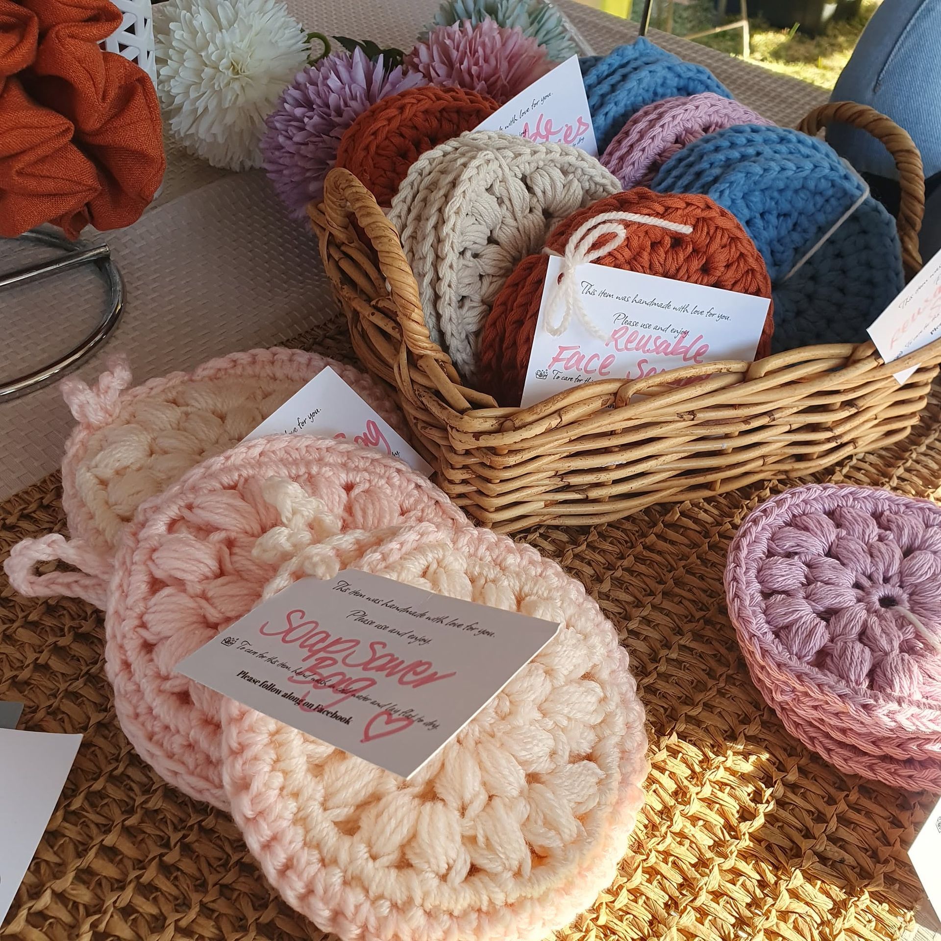 Wicker basket of colorful crocheted scrubbies and soap pouches on a woven tablecloth — Tilligerry Collective in Tanilba Bay, NSW
