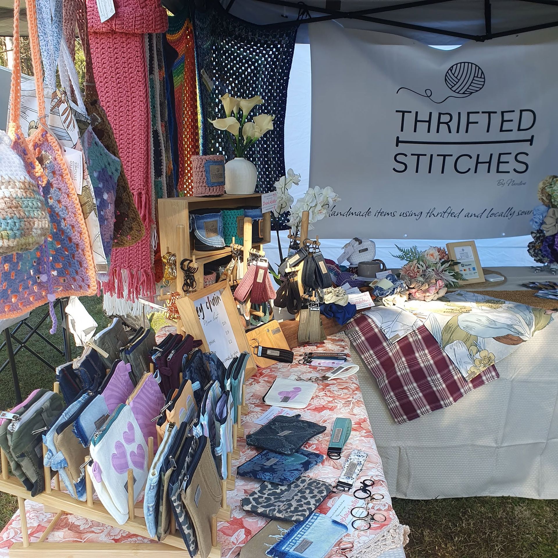 Thrifted Stitches booth with colorful handmade quilts, scarves, and table display at a market stall — Tilligerry Collective in Tanilba Bay, NSW