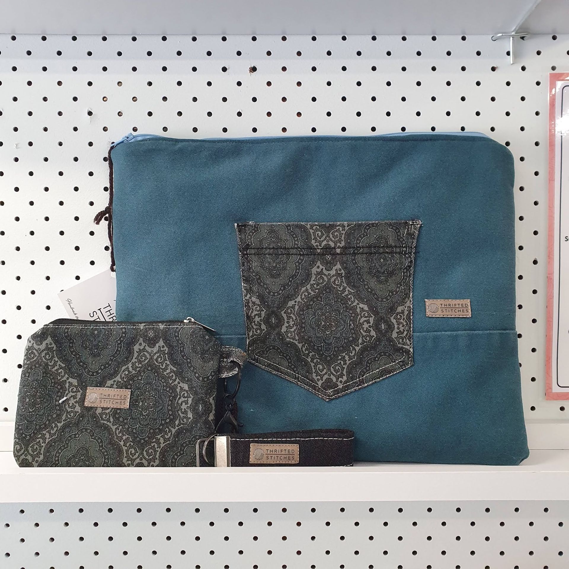 Blue fabric pouch with dark patterned pockets on a white pegboard shelf — Tilligerry Collective in Tanilba Bay, NSW