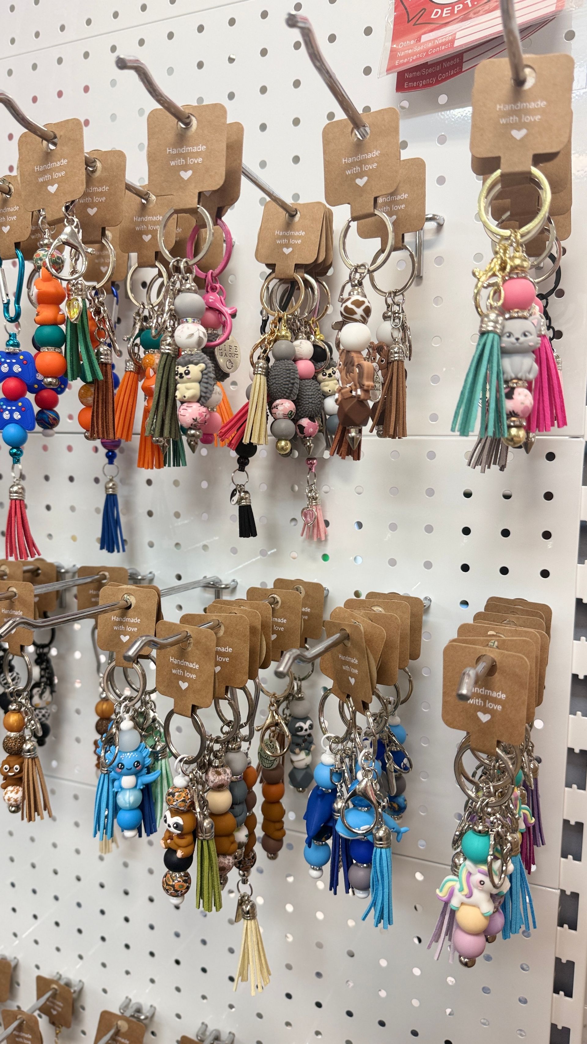 Assorted colourful keychains and tassel charms displayed on a pegboard wall. — Tilligerry Collective in Tilligerry Peninsula, NSW