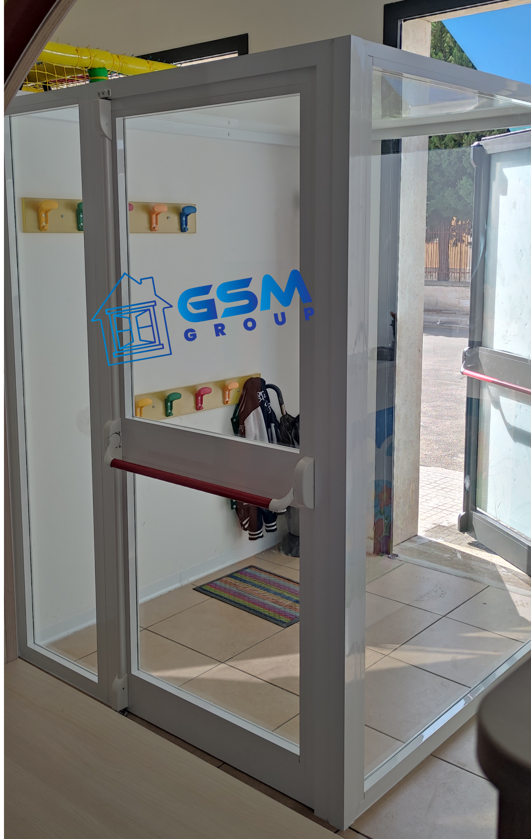 Struttura di porta a vetri con telaio bianco e barra antipanico, con logo 