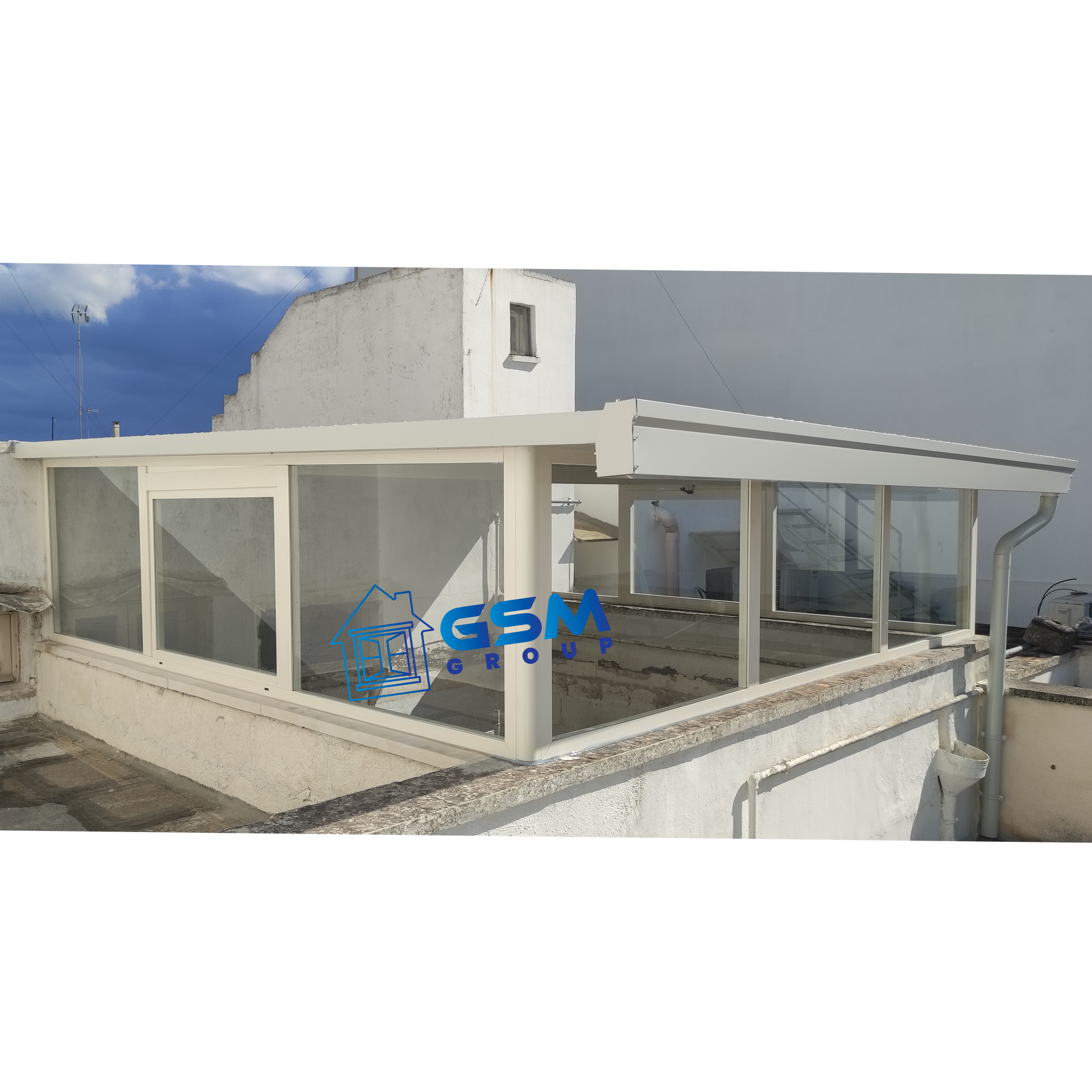 Una serra in vetro bianco o una struttura coperta con tettoia, installata su una terrazza con tetto piano addossata a un edificio bianco.