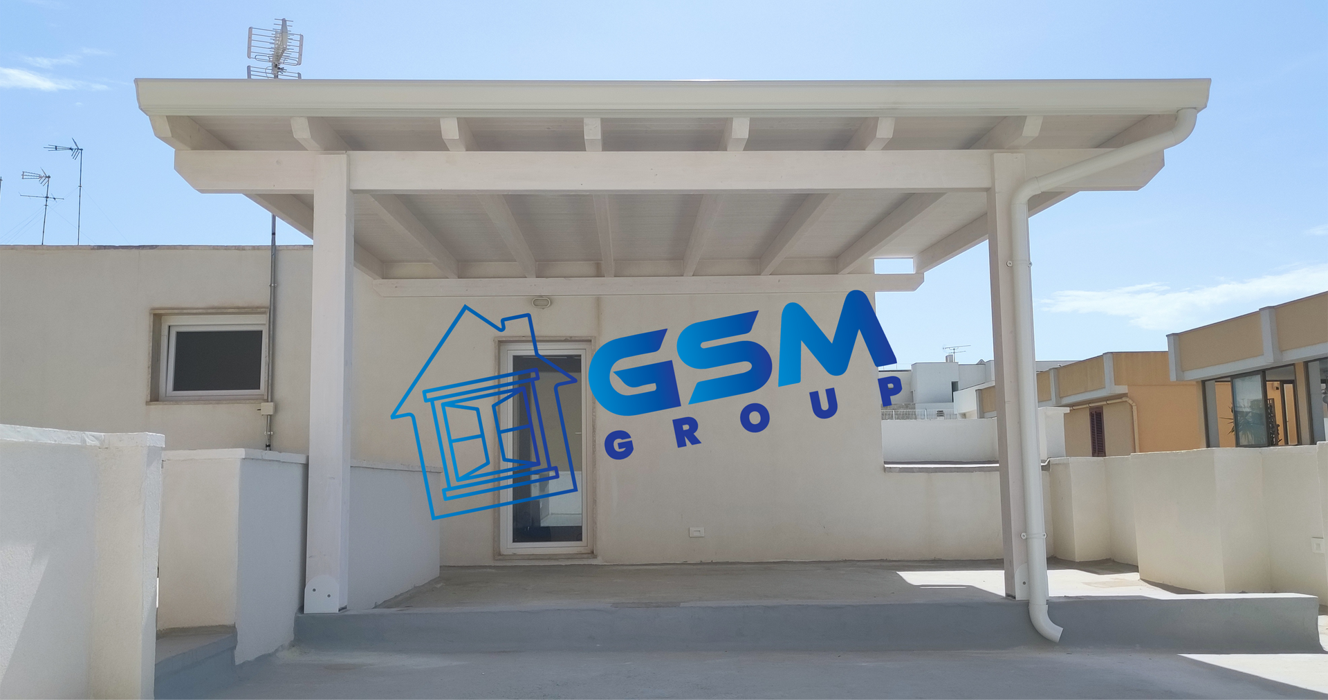Una pergola bianca copre una terrazza annessa a un edificio, con il logo blu