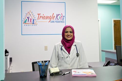 Woman in lab coat and hijab at desk with