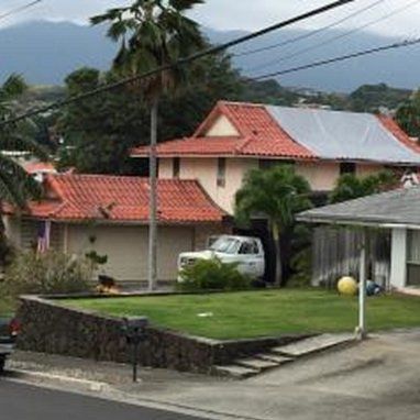 A white truck is parked in front of a house with a red tile roof.