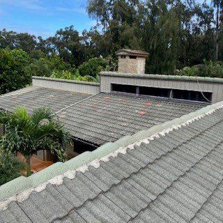 A roof with a chimney on top of it and trees in the background.