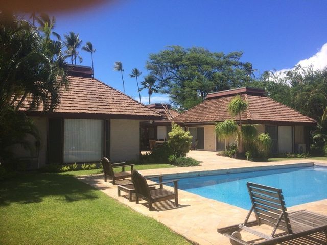 There is a large swimming pool in front of a house.